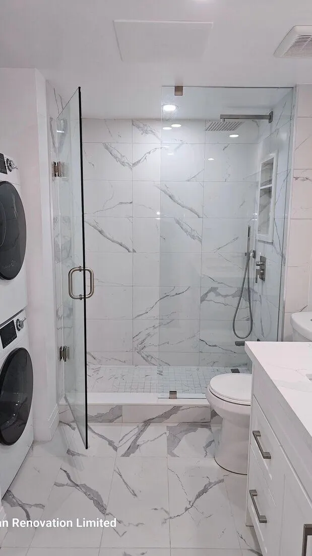 Marble-look walk-in shower beside a stacked washer and dryer